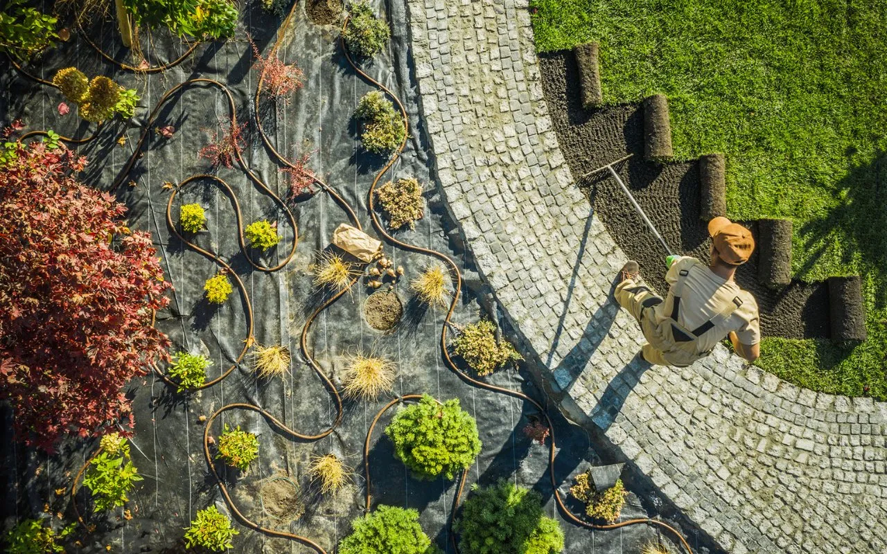 irrigation system at the left, person working on lawn at the right - professional landscaping utah